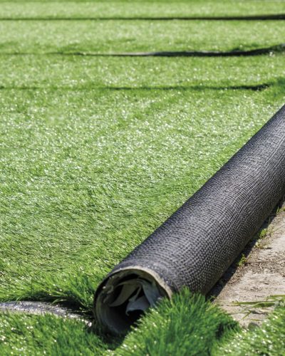 green artificial covering of synthetic grass in rolls on the future football field